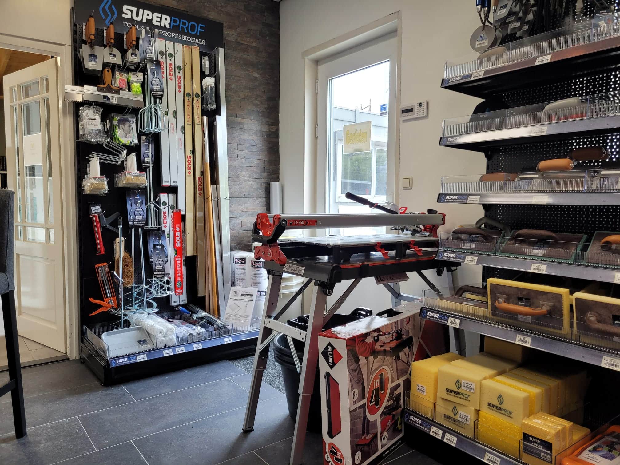 Superprof display met een tegelsnijder op een werkbank en schappen met gereedschap