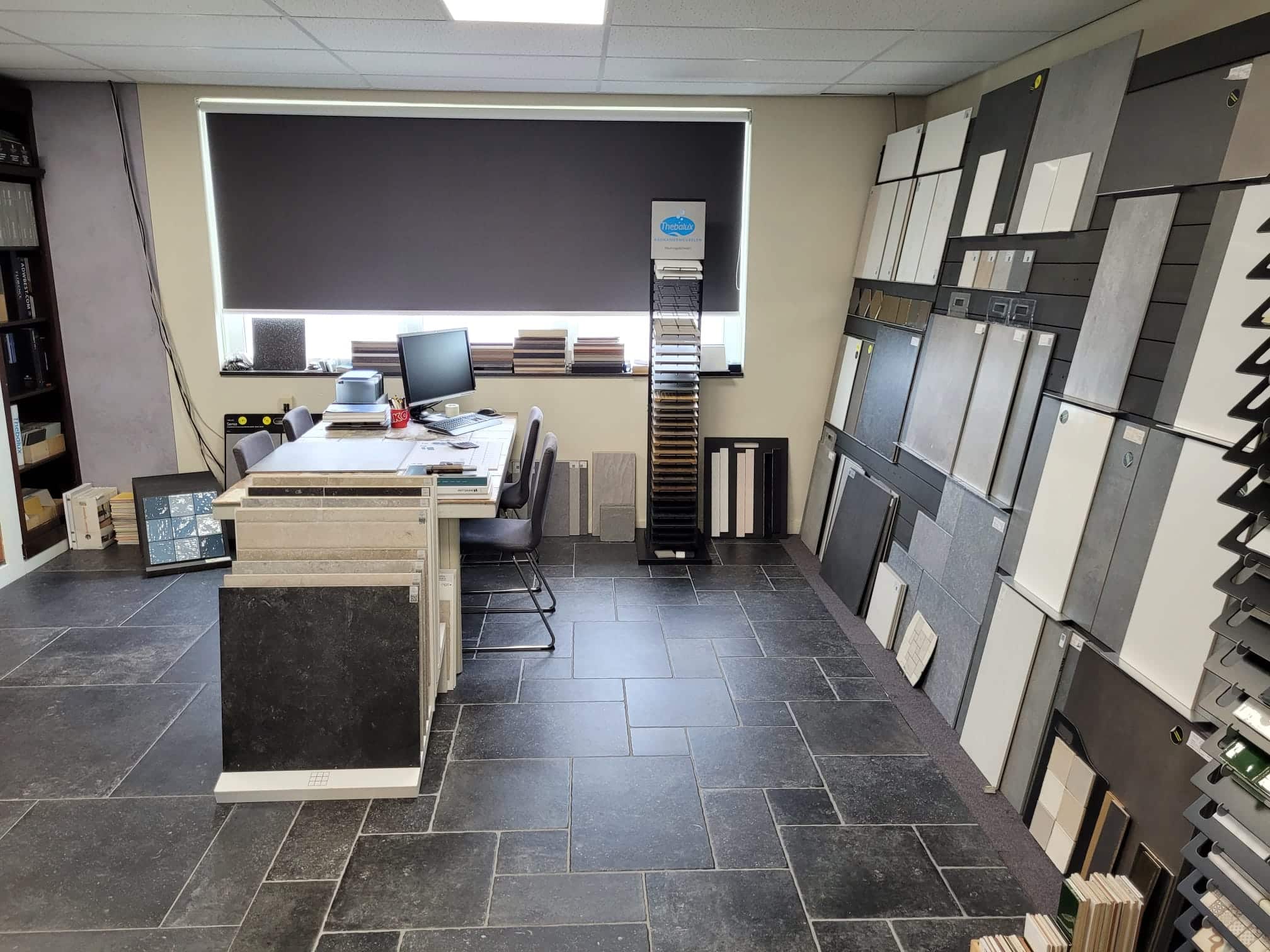 Adviesbalie met beeldschermen in de showroom, met grote wand- en vloertegels aan de wand